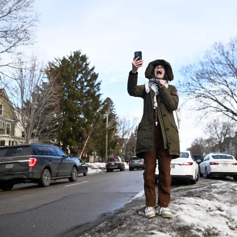 A person yells while holding up a cell phone.