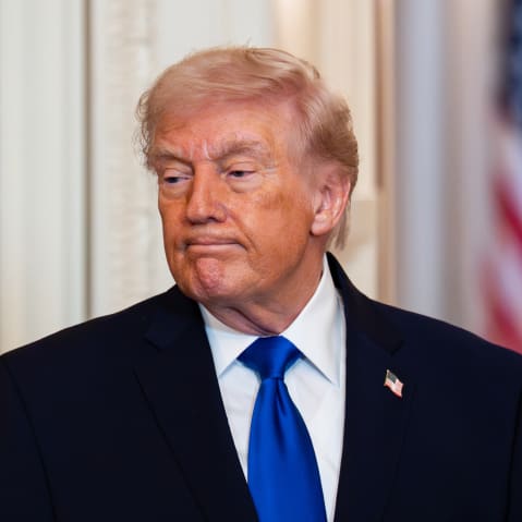 Donald Trump looks down with a negative facial expression.