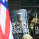 A demonstrator holds an upside down US flag as they face California National Guard.