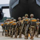 Soldiers walk into an airplane parked on the tarmac outside