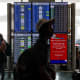 Travelers walk past the flight information display system at Los Angeles International Airport/