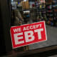 A store displays a sign accepting Electronic Benefits Transfer (EBT) cards for Supplemental Nutrition Assistance Program (SNAP) purchases.