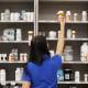 A pharmacy technician grabs a bottle of drugs off a shelf at a pharmacy