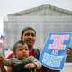 Olga Urbina holds a sign that reads "American Born Children are American Children" as her son Aers holds an American flag.