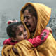 A woman holding a girl reacts after Israeli airstrikes hit
