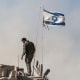 An Israeli soldier stands on the top of a tank parked
