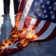 An American flag burns on the ground