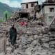 An man Afghan walks past a damaged house following earthquake.