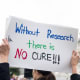 A protesters holds a sign that reads, "Without Research There Is No Cure" outside the Capitol