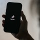 A person holds a phone with the TikTok logo.