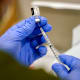 A healthcare worker fills a syringe.