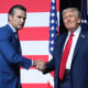 Pete Hegseth, left, shakes hands with Donald Trump on stage