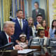 President Donald Trump is joined by childhood cancer survivors and their families in the Oval Office on Sept. 30, 2025.