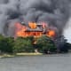 A view of a home on fire near a body of water.