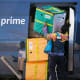 An Amazon Prime delivery person lifts packages while making a stop