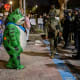 A protester in a frog costume stands in front of a line of federal law enforcement officers outside a United States Immigration and Customs Enforcement (ICE) facility.