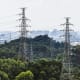 High angle view of cityscape with forest area and high voltage electricity pylon.