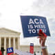 A person holds at sign that reads "ACA Is Here To Stay" at the Supreme Court