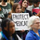 A woman holds a sign that reads "Protect Medicaid"