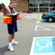 Volunteer handicapped parking enforcement officer writes a parking ticket for a car parked without a handicapped plate or place card.