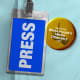 A press pass seen beside a button with a thumb's up that says "I'm on the White House Media Offender's List"