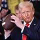 President Donald Trump holds up a football presented to him during a presentation ceremony for the Commander-in-Chief Trophy in the White House on April 15, 2025.