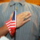 A person holds their hand up to their chest as they swear allegiance to the U.S. flag during a naturalization ceremony in Miami, F.L., on April 28, 2006.