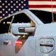 A Ford Motor Co. F-150 Lightning EV in front of an American flag.