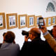 Members of the media take photographs of framed portraits part of the "Presidential Walk of Fame" on the wall of the colonnade outside the Oval Office.