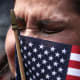 A woman tears up with a small American flag obscuring part of her face.
