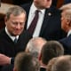 President Trump, right, pats Chief Justice Roberts arm ina crowd of people.