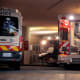 Two ambulances and a gurney in the ambulance bay of a hospital.