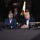President Donald Trump, center, sits with his hands folded.