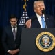Secretary of State Marco Rubio looks down as President Donald Trump speaks behind a podium.