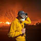 MS NOW's Jacob Soboroff stands with a microphone, wearing a face mask as Palisades fire continues in the background.