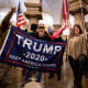 People within the Capitol hold flags supporting Donald Trump.