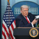 President Trump holds up a folder of documents as he speaks to the media during a briefing.