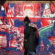 A woman walks by a red and blue mural that sends an anti-american message.