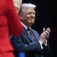 Donald Trump claps with a smile on his face.