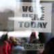 A Vote Here sign seen on a window.