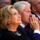 Hillary Clinton, left, looks up as she sits next to her husband Bill Clinton.