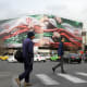 A photo showing daily life in Tehran where two men crossing the street with a big iranian flag seen on a billboard in the background.