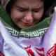 A young woman, wrapped in an Iranian flag, cries.