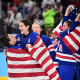 Hockey players in jerseys that read "USA" celebrate with American flags.