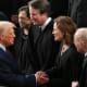 Donald Trump shakes Amy Coney Barrett's hand. They are surrounded by other Supreme Court justices.