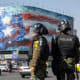 Twon officers stand in the street while a big billboard is seen in the background.