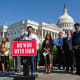 Greg Casar stands behind a podium that has a red sign that says "NO WAR WITH IRAN." He is surrounded by other people, and in the background is the Capitol.