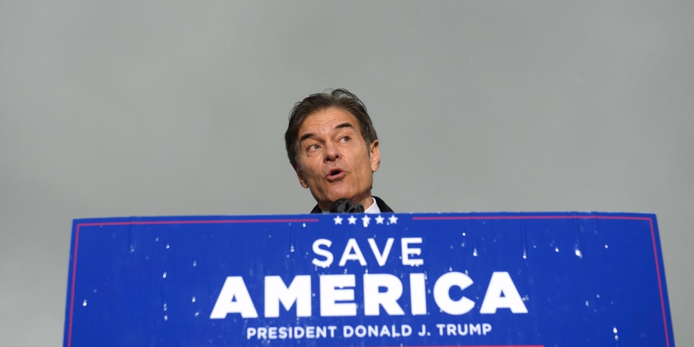 Image: Dr. Mehmet Oz standing behind a podium with a sign that reads,"Save America, President Donald j. Trump".