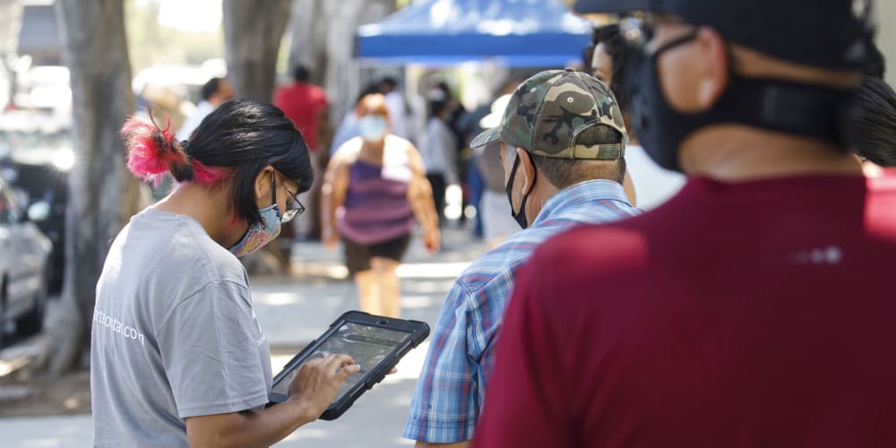 Image: A youth ambassador conducting a census interview with people walking by.