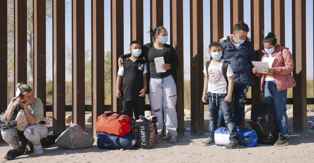 Image: Asylum seekers wait to be processed by the Customs and Border Protection, next to the border wall between Mexico and the U.S in Yuma, Arizona.